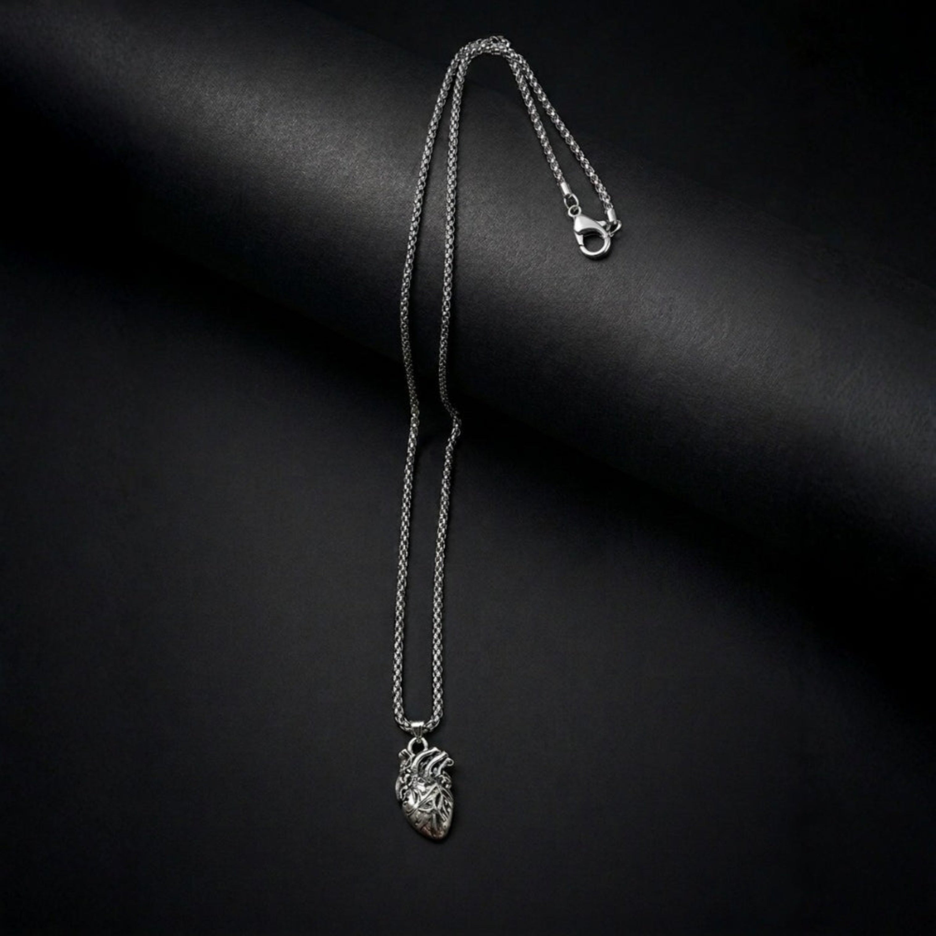 Silver necklace with a heart pendant on a black background